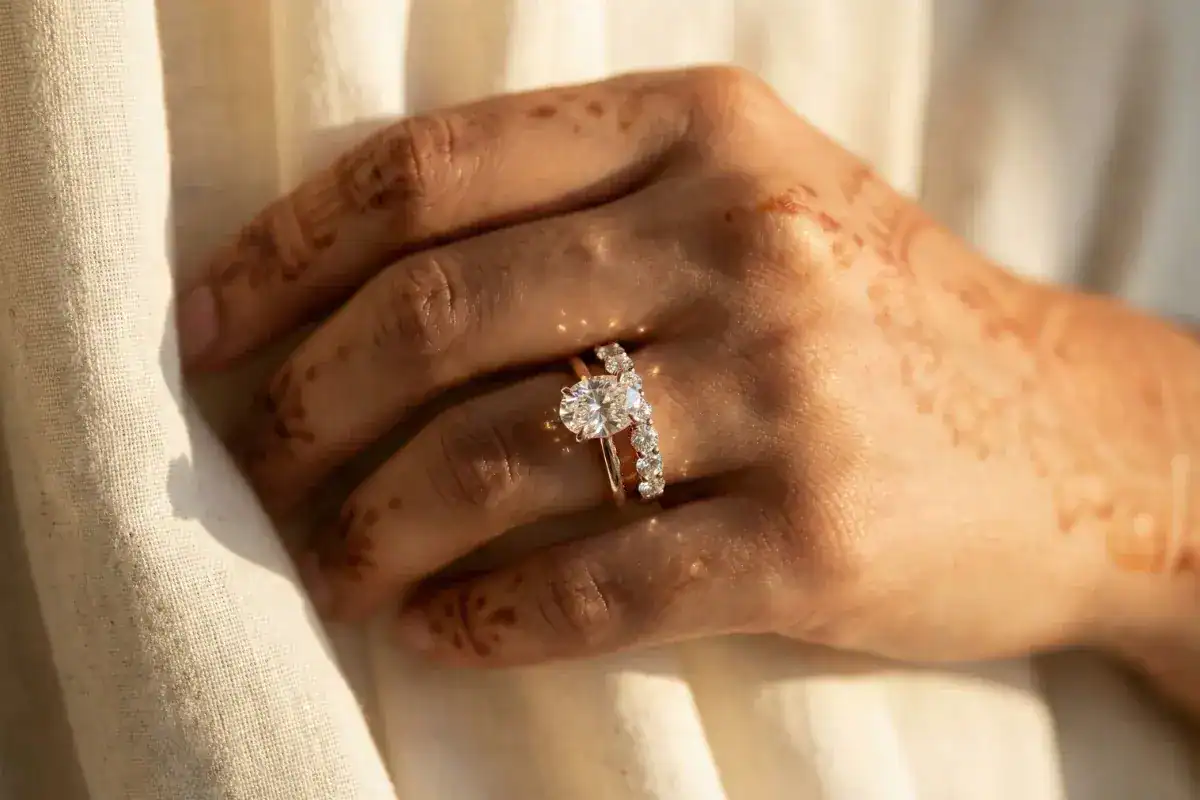 Lab grown diamond band stacked with solitaire engagement ring on Indian woman hand with henna