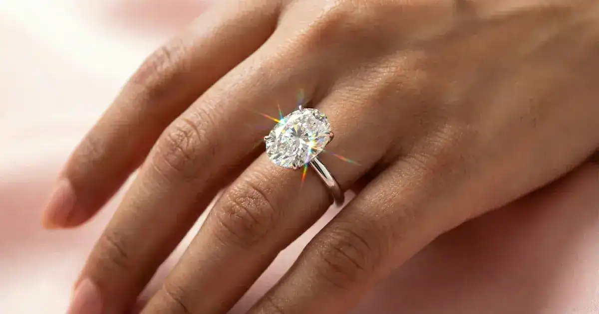 Oval solitaire engagement ring with labgrown diamond in 18K white gold on woman's hand